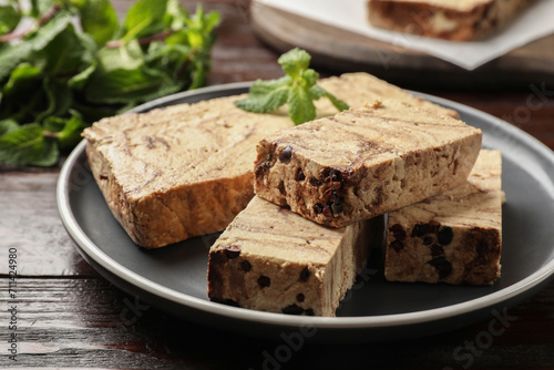 Pieces of tasty chocolate halva with mint on wooden table, closeup