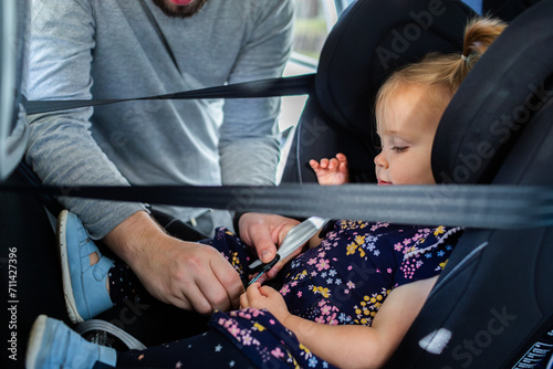 Dad buckling toddler into extended rear facing car seat photo