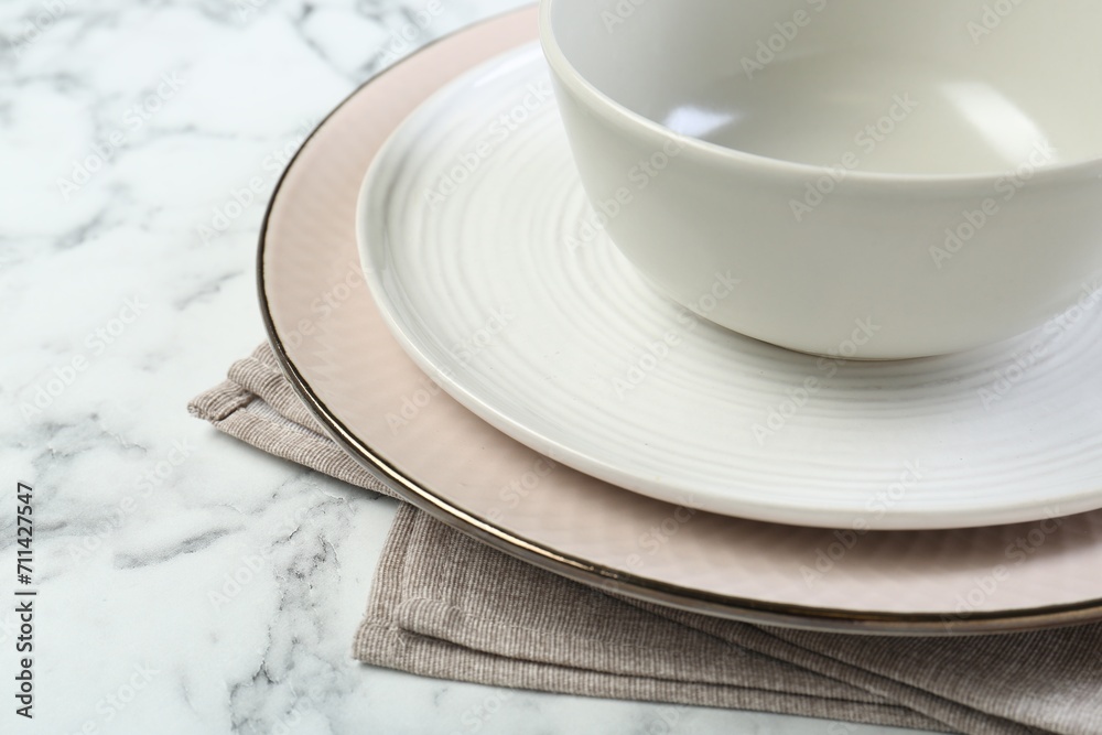 Clean plates, bowl and napkin on white marble table, closeup. Space for text