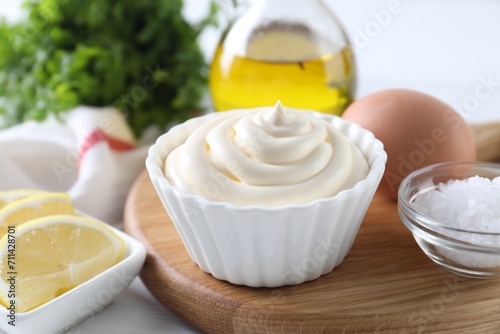 Fresh mayonnaise sauce in bowl and ingredients on table, closeup