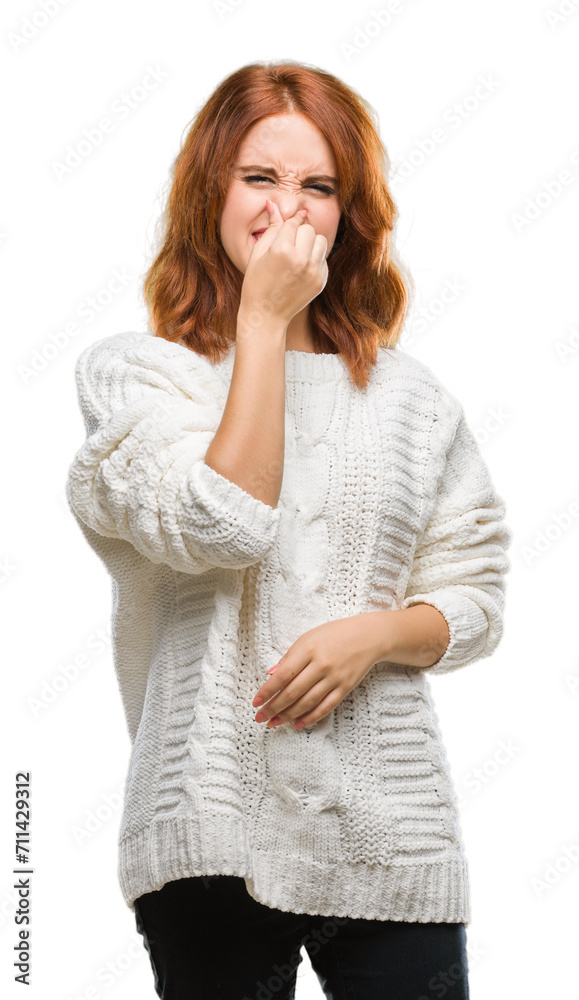 Young beautiful woman over isolated background wearing winter sweater smelling something stinky and disgusting, intolerable smell, holding breath with fingers on nose. Bad smells concept. Young beautiful woman over isolated background wearing winter sweater smelling something stinky and disgusting, intolerable smell, holding breath with fingers on nose. Bad smells concept.