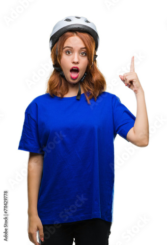 Young beautiful woman wearing cyclist helmet over isolated background pointing finger up with successful idea. Exited and happy. Number one.