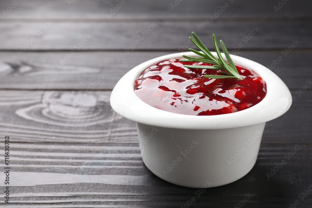 Fresh cranberry sauce in bowl and rosemary on black wooden table, closeup. Space for text Fresh cranberry sauce in bowl and rosemary on black wooden table, closeup. Space for text