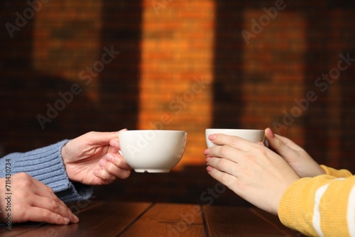 Women having coffee break at wooden table in cafe, closeup