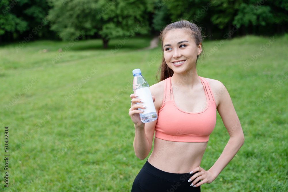 Morning exercise. Sporty and energetic young woman standing on green meadow, holding a water bottle, embracing a healthy and active lifestyle in nature. Morning exercise. Sporty and energetic young woman standing on green meadow, holding a water bottle, embracing a healthy and active lifestyle in nature.