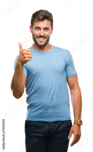 Young handsome man over isolated background doing happy thumbs up gesture with hand. Approving expression looking at the camera with showing success.