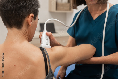 Medical professional performing an ultrasound on a patient's shoulder photo