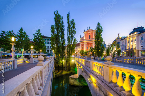 Evening lights illuminate the Tromostovje bridge and Franciscan Church of the Annunciation in Ljubljana's city center photo