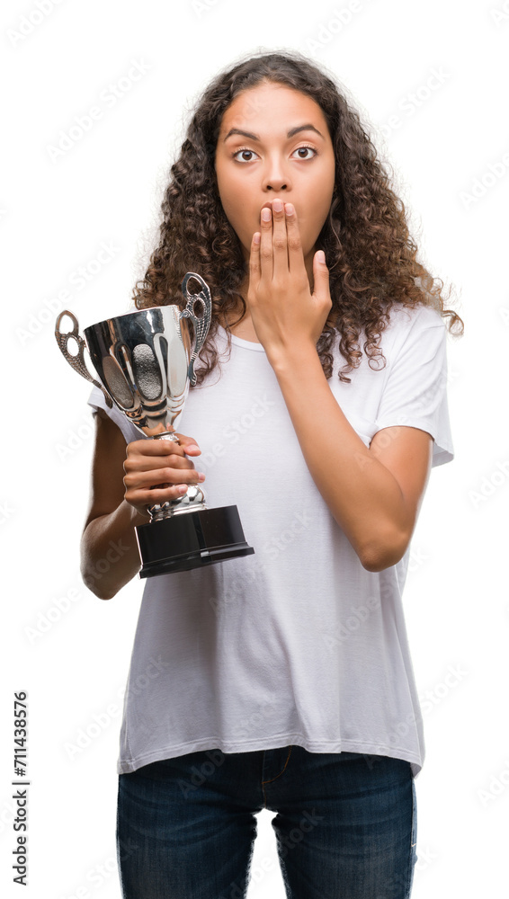 Young hispanic woman holding trophy cover mouth with hand shocked with shame for mistake, expression of fear, scared in silence, secret concept Young hispanic woman holding trophy cover mouth with hand shocked with shame for mistake, expression of fear, scared in silence, secret concept