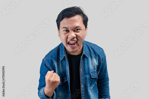Young Asian Man raised his fist with a happy smile on his face as a gesture of celebration. On isolated background