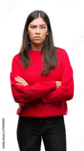 Young beautiful hispanic wearing red sweater skeptic and nervous, disapproving expression on face with crossed arms. Negative person.