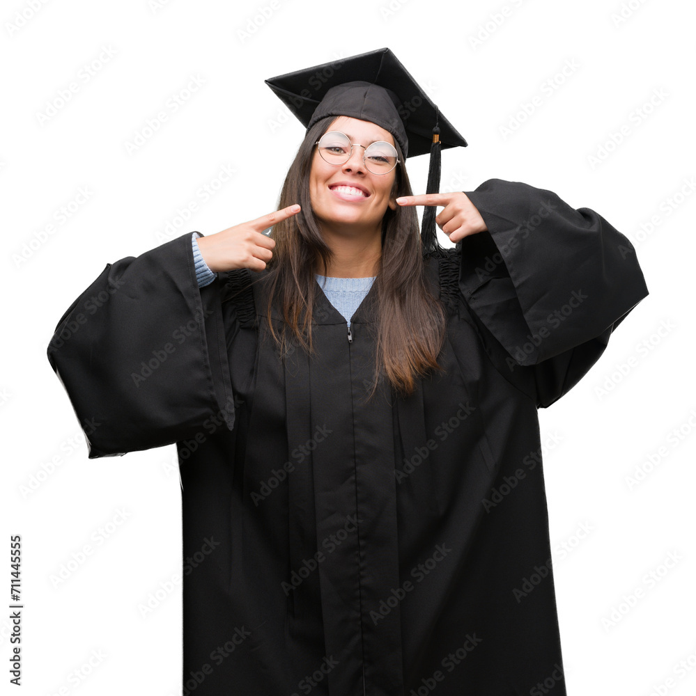 Young hispanic woman wearing graduated cap and uniform smiling confident showing and pointing with fingers teeth and mouth. Health concept. Young hispanic woman wearing graduated cap and uniform smiling confident showing and pointing with fingers teeth and mouth. Health concept.