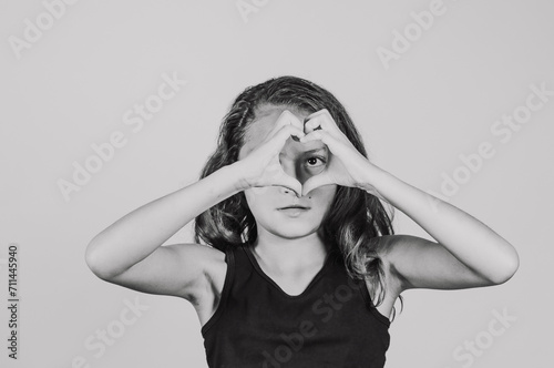 A tween Hispanic girl with her hands forming a heart shape.