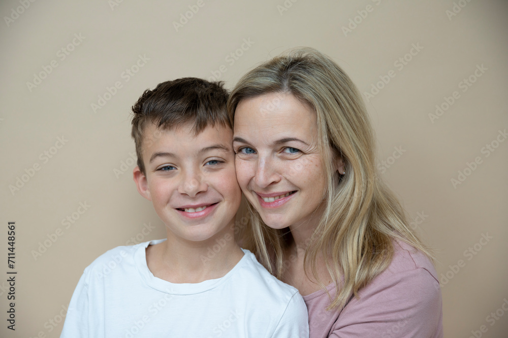 cool young teenager boy with white t-shirt posing together with his beautiful mother in front of brown background cool young teenager boy with white t-shirt posing together with his beautiful mother in front of brown background