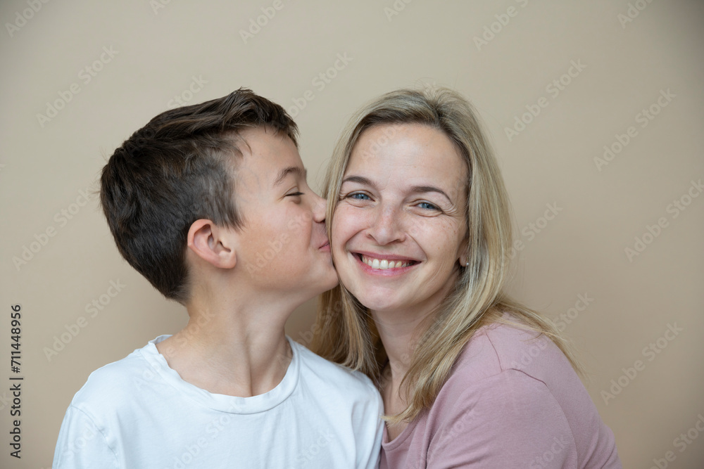 cool young teenager boy with white t-shirt posing together with his beautiful mother in front of brown background cool young teenager boy with white t-shirt posing together with his beautiful mother in front of brown background
