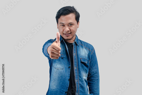 Young Asian Man showing thumb up in approval, recommending, like smth good, standing over white background