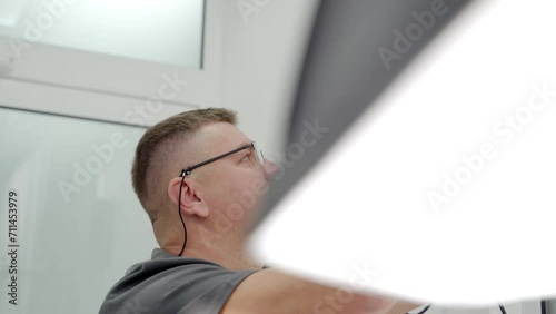 Close-up of male dentist preparing lighting equipment to taking photo of patient in modern dental clinic. Photographer fixes a soft box. Doctor prepares light before shooting. Cosmetic dentistry. photo