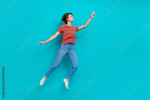 Full length photo of charming funky girl wear trendy outfit hold announcement empty space isolated on cyan color background