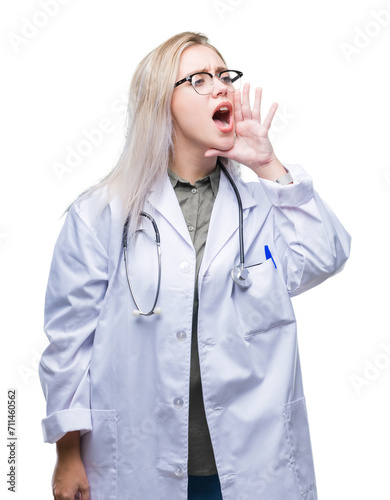 Young blonde doctor woman over isolated background shouting and screaming loud to side with hand on mouth. Communication concept.