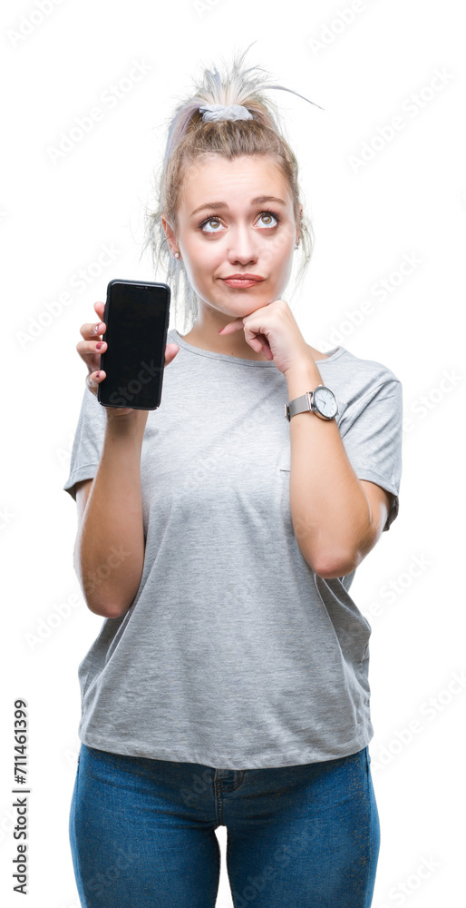 Young blonde woman showing screen of smartphone over isolated background serious face thinking about question, very confused idea Young blonde woman showing screen of smartphone over isolated background serious face thinking about question, very confused idea