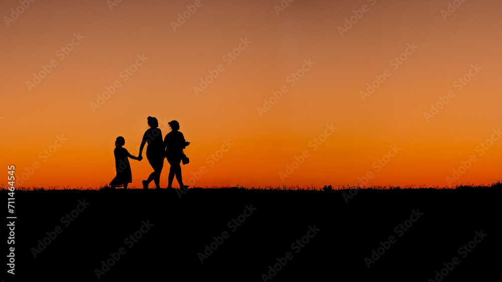 Mother with daughters walking at sunset on the shore of the Ohio River