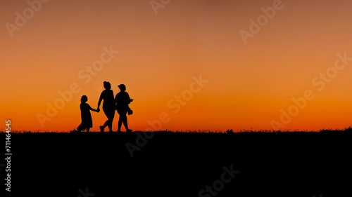Mother with daughters walking at sunset on the shore of the Ohio River
