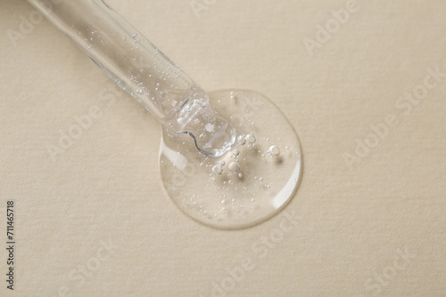 Pipette with cosmetic serum on beige background, macro view