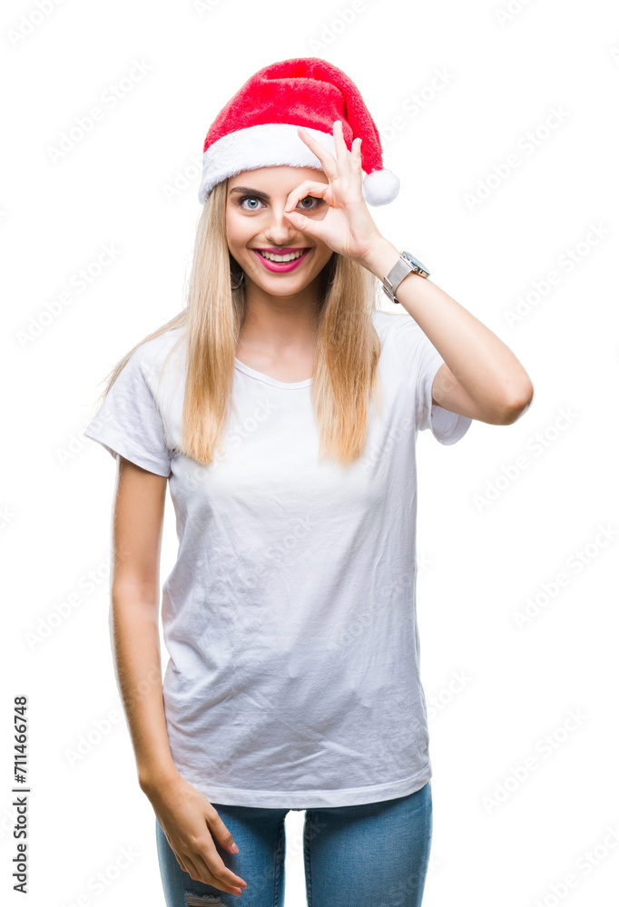 Young beautiful blonde woman christmas hat over isolated background doing ok gesture with hand smiling, eye looking through fingers with happy face. Young beautiful blonde woman christmas hat over isolated background doing ok gesture with hand smiling, eye looking through fingers with happy face.