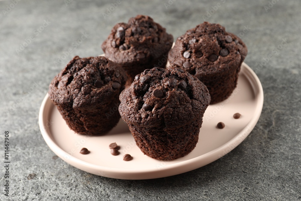 Delicious chocolate muffins on grey textured table Delicious chocolate muffins on grey textured table