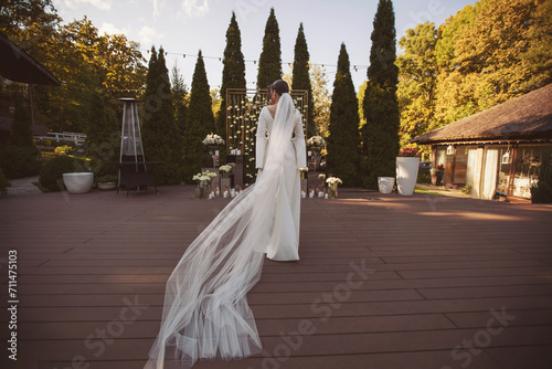 Back of a young bride in white lace wedding dress with black hair and a bouquet in her hands ,bride's morning, fine art wedding. Bride in a dress, wedding dress, wedding decorations on background.