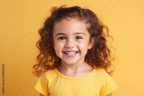 Portrait of a cute little girl with curly hair on yellow background © Loli