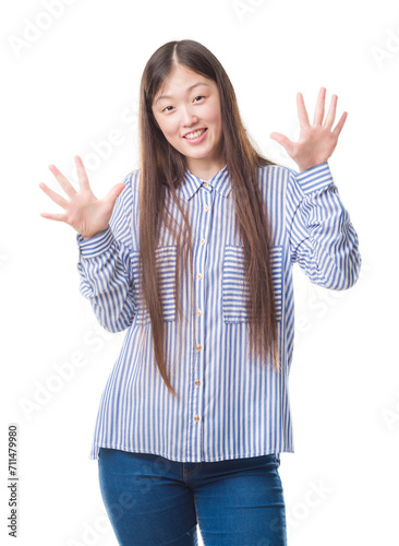 Young Chinese woman over isolated background showing and pointing up with fingers number ten while smiling confident and happy.