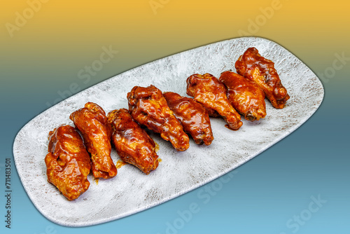 Plate of barbecued chicken wings on a yellow and light blue gradient background