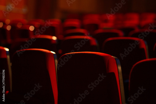 Detalhe de um teatro vazio. Várias fileiras de poltronas vermelhas fotografadas por trás. Fotografia com foco restrito. photo