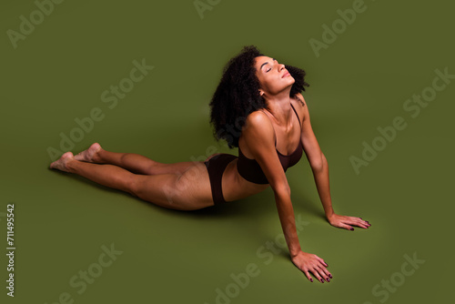 No retouch photo of charming sporty girl stretching on floor yoga pilates aerobics isolated over khaki color background