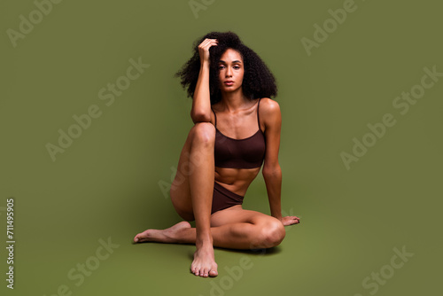 No retouch photo of stunning aesthetic lady sporty slim thin shape sitting floor isolated over khaki color background