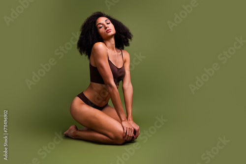 No filter profile of stunning sexual girl gymnast sitting on floor empty space isolated over khaki color background