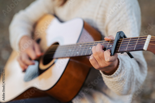 Guitar in hands of a young woman playing it. Playing music outdoors, using equipment capo photo