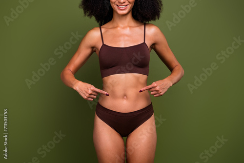 Cropped no retouch photo of charming slender girl showing her thin waist isolated on khaki color background photo