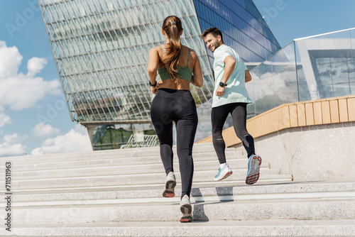 Energetic couple running up steps outside a modern glass building  showcasing active urban living.