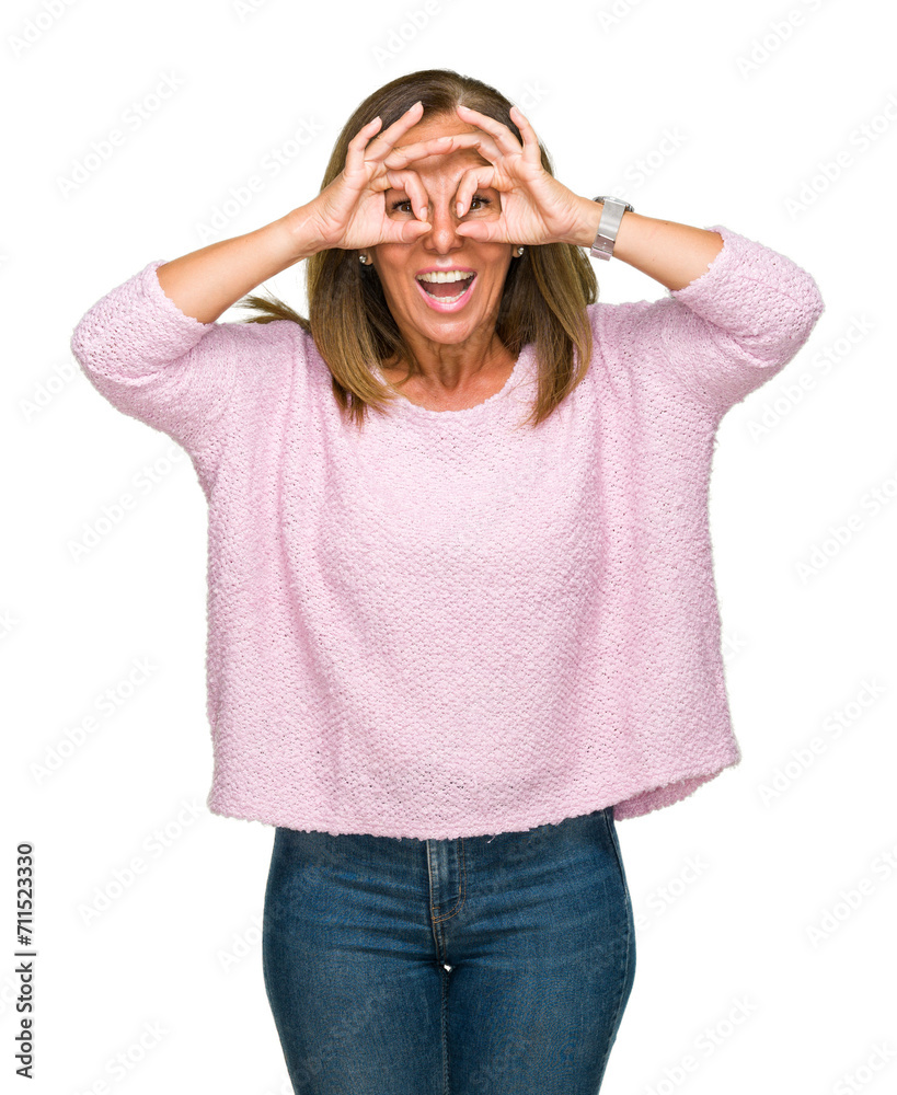 Beautiful middle age adult woman wearing winter sweater over isolated background doing ok gesture like binoculars sticking tongue out, eyes looking through fingers. Crazy expression.