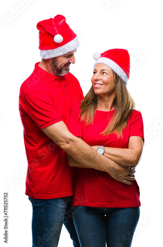 Middle age hispanic couple wearing christmas hat over isolated background with serious expression on face. Simple and natural looking at the camera.