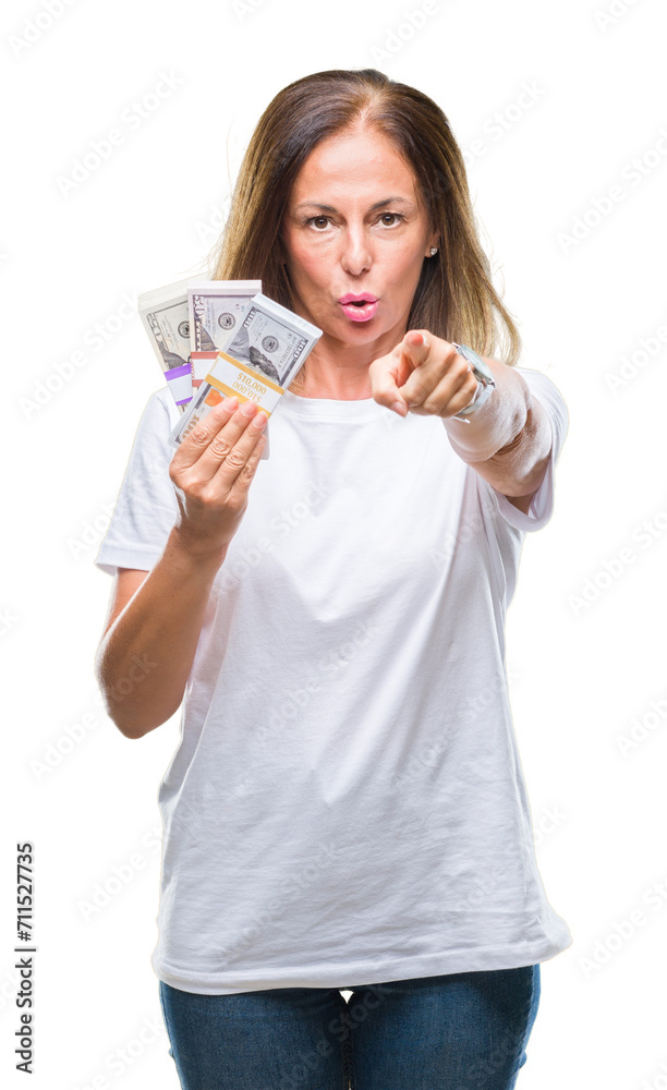 Middle age hispanic woman holding bunch of dollars over isolated background pointing with finger to the camera and to you, hand sign, positive and confident gesture from the front Middle age hispanic woman holding bunch of dollars over isolated background pointing with finger to the camera and to you, hand sign, positive and confident gesture from the front