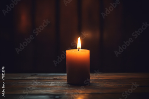 A single candle burning in a dim room - symbolizing the enduring memory and presence of someone dearly missed who has passed away. photo