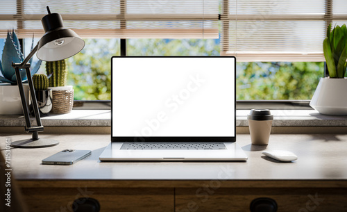 A laptop with a blank screen sits on a stylish wooden desk within a loft-style interior, with green spaces in the background visible through the window. Transparent screen - 3d render