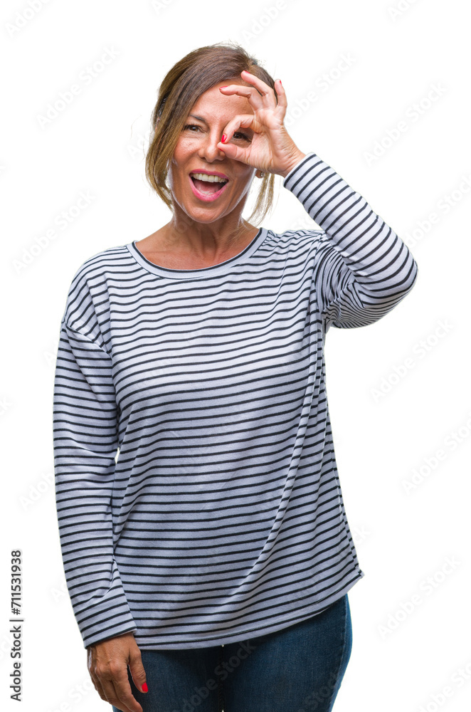 Middle age senior hispanic woman over isolated background doing ok gesture with hand smiling, eye looking through fingers with happy face.
