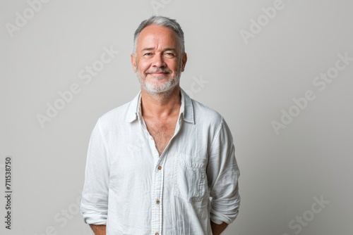 Portrait of smiling mature man standing on white background. © darshika