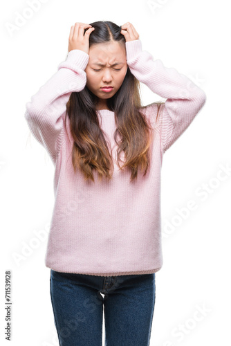 Young asian woman over isolated background suffering from headache desperate and stressed because pain and migraine. Hands on head. © Krakenimages.com