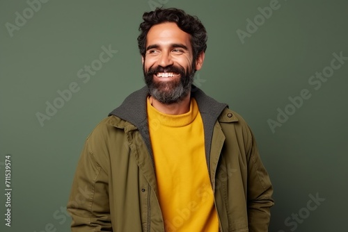 Portrait of a handsome bearded man smiling at camera against green background