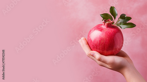 Hand holding pomegranate fruit isolated on pastel background